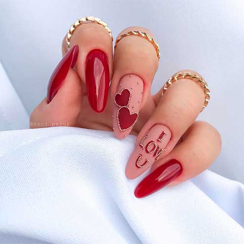 Dark-red-valentines-day-nails-design-adorned-with-red-heart-shaped-and-some-rhinestones-over-two-nude-colored-accent-nails